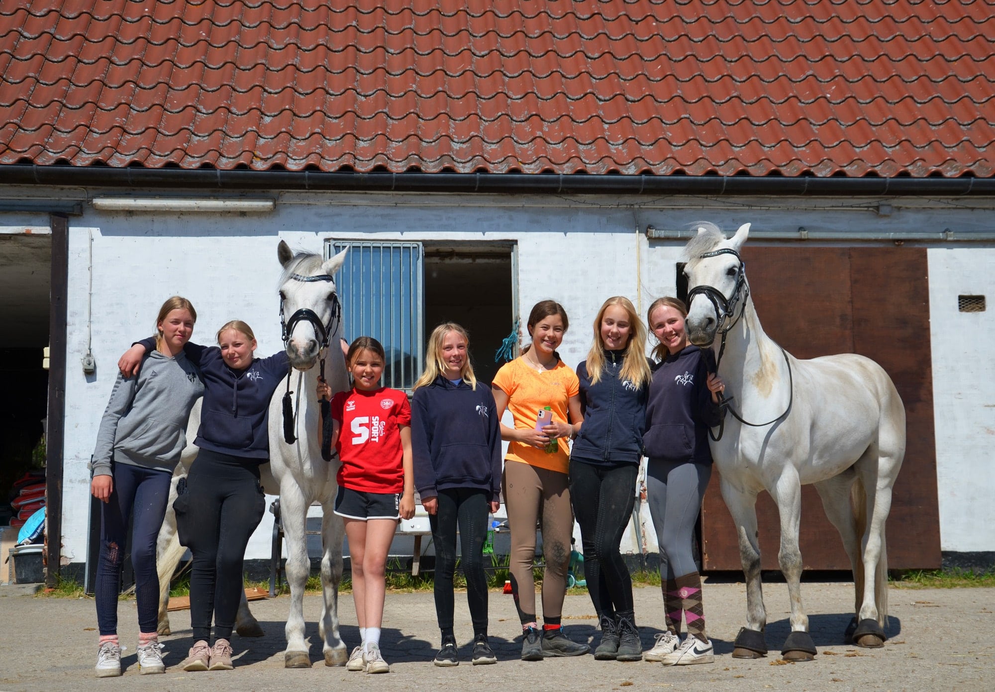 Birkerød Rideforening medlemmer smiler med hvide heste for at samle ind til nyt rideudstyr med skrabelodder